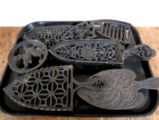 A tray containing seven antique cast iron trivets