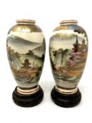 A pair of Japanese Meiji period Satsuma earthenware vases on turned hardwood stands,