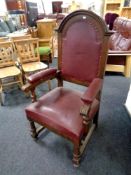 An Edwardian oak high backed armchair upholstered in a red vinyl