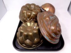 A tray containing three antique copper jelly moulds together with a further copper dish