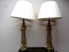 A pair of ornate gilt metal table lamps with shades,