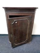 A late 18th/early 19th century oak panel door hanging corner cabinet