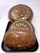 A tray containing three antique copper jelly moulds