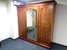 A Victorian mahogany triple door wardrobe with central mirrored door fitted drawers and tray,