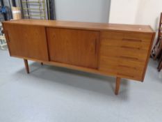 A 20th century teak sliding door sideboard fitted five drawers retailed by Chapman's,