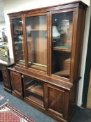 A Victorian mahogany triple door glazed bookcase fitted cupboards beneath,