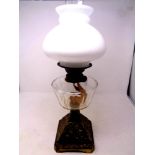An antique brass oil lamp with clear glass reservoir, chimney and shade,