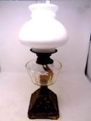 An antique brass oil lamp with clear glass reservoir, chimney and shade,