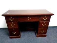 A Victorian style mahogany seven drawer kneehole desk with brass drop handles,