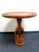A carved eastern occasional table on elephant pedestal