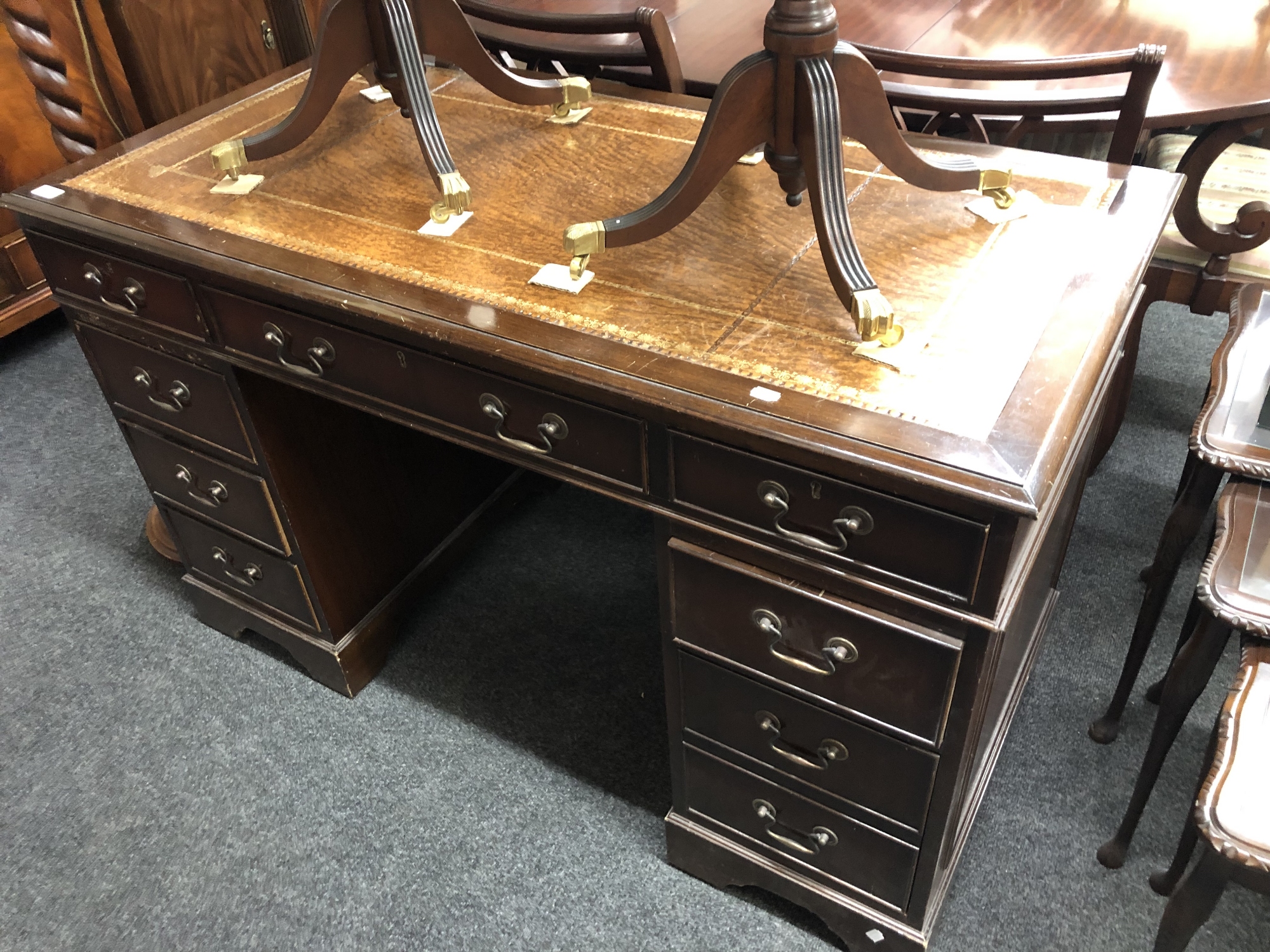 A Regency style twin-pedestal writing desk fitted nine drawers with a brown leather inset panel,