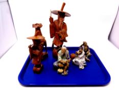 A tray containing oriental bisque porcelain figures, carved wooden figures,