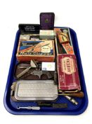A tray containing safety razors, lighters, policeman's whistle, corkscrew in the form of a gun,