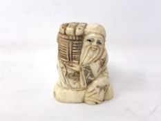 A Japanese carved bone netsuke - Village elder carrying a basket of wares on his shoulder.