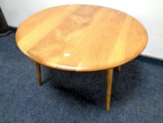 A 20th century Ercol solid elm and beech circular coffee table on raised legs,