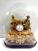 A gilt metal continental mantel clock with enamel dial, pendulum and key, under a glass dome,