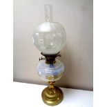 An antique brass oil lamp with hand painted opaque glass reservoir, chimney and shade,