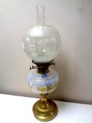 An antique brass oil lamp with hand painted opaque glass reservoir, chimney and shade,