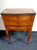 A French marquetry inlaid three drawer side table on raised legs with a marble inset panel