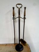 An antique brass two piece fire companion set on stand