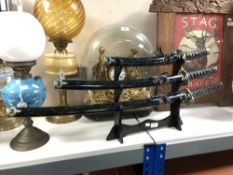 Three graduated reproduction samurai swords on stand