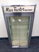 A 20th century metal framed sliding glass door display cabinet bearing Max Factor Hollywood