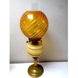 An antique brass oil lamp with glass reservoir, chimney and amber shade, height 65.