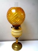 An antique brass oil lamp with glass reservoir, chimney and amber shade, height 65.