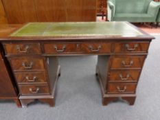 A reproduction mahogany nine drawer twin pedestal desk with a green tooled leather inset panel
