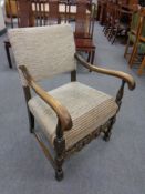 A carved beechwood armchair upholstered in a beige fabric