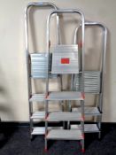 Two aluminium folding four tread stepladders together with a further three tread stepladder