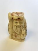 A Japanese carved bone netsuke - village elder carrying a staff