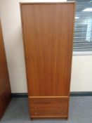 A mid 20th century teak effect single door wardrobe fitted three drawers beneath,