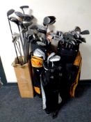 Three golf bags and a box containing a large quantity of assorted drivers,