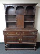 An antique carved oak dresser fitted cupboards and drawers beneath