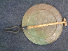 A rustic hayfork together with a circular Egyptian design copper plaque