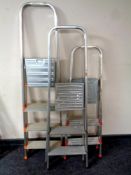 Two aluminium three tread folding stepladders together with a further aluminium four tread folding