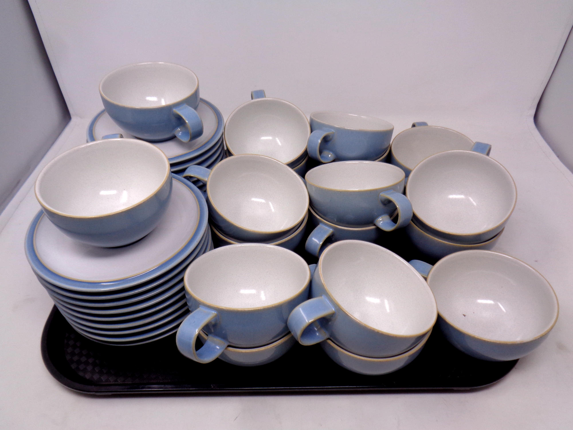 A tray containing eighteen Denby Colonial Blue teacups and saucers