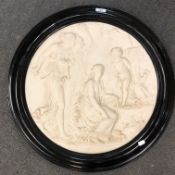 An ornate ceramic circular wall plaque : Three Maidens with Cherub in a Garden, framed in black,