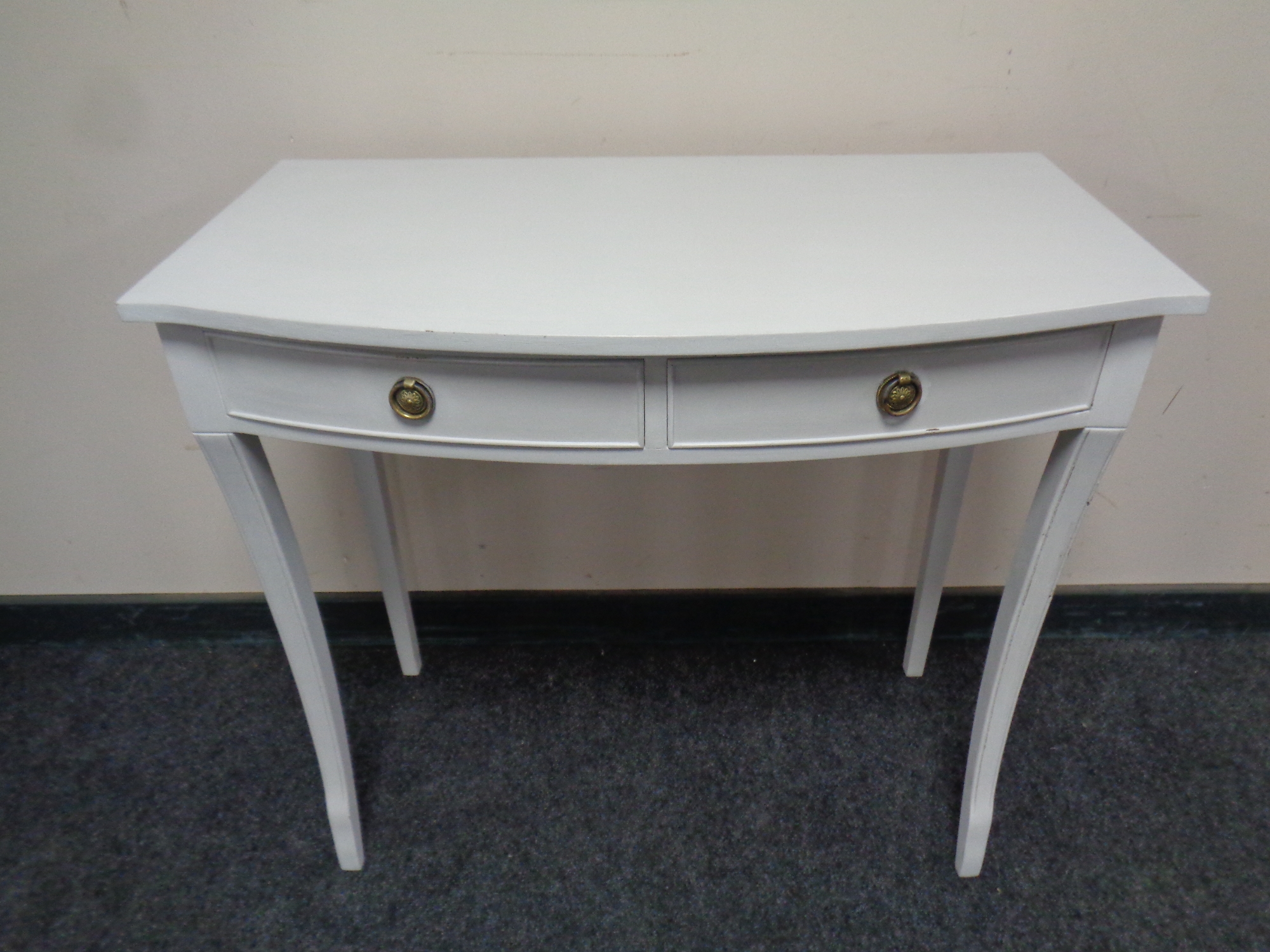 A serpentine fronted two drawer console table on raised legs