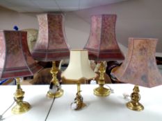 A pair of brass table lamps together with three further brass lamps,