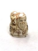 A Japanese craved bone netsuke : A village elder carrying a sack on his shoulder.