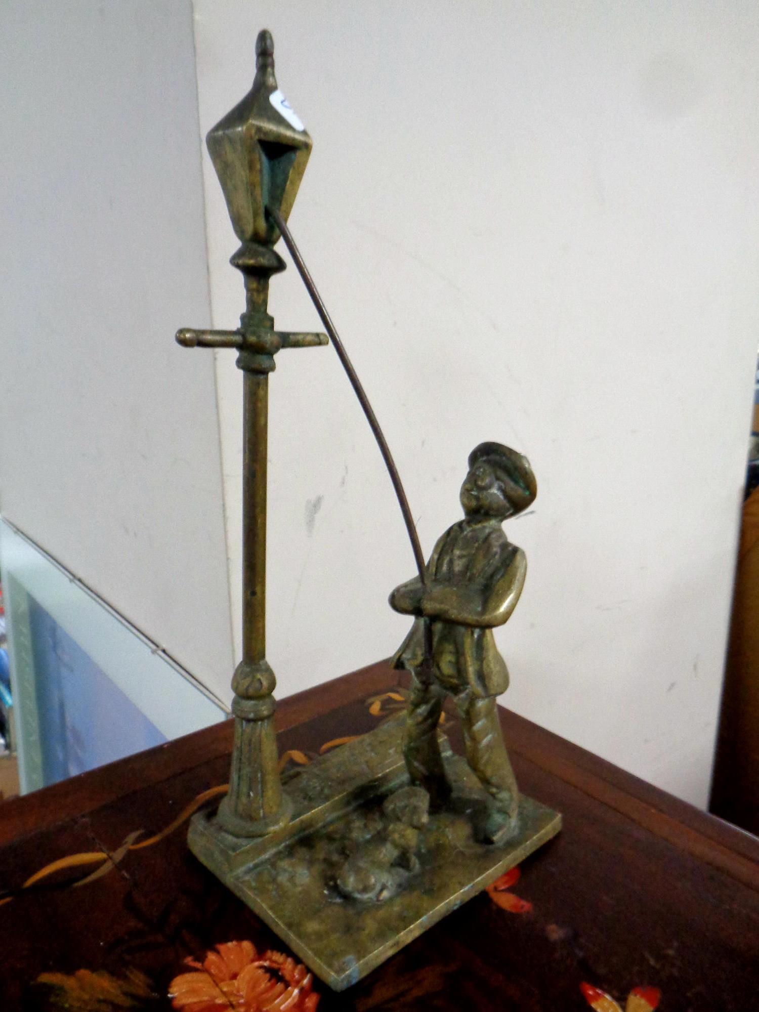 A brass figure of a lamp lighter with dog