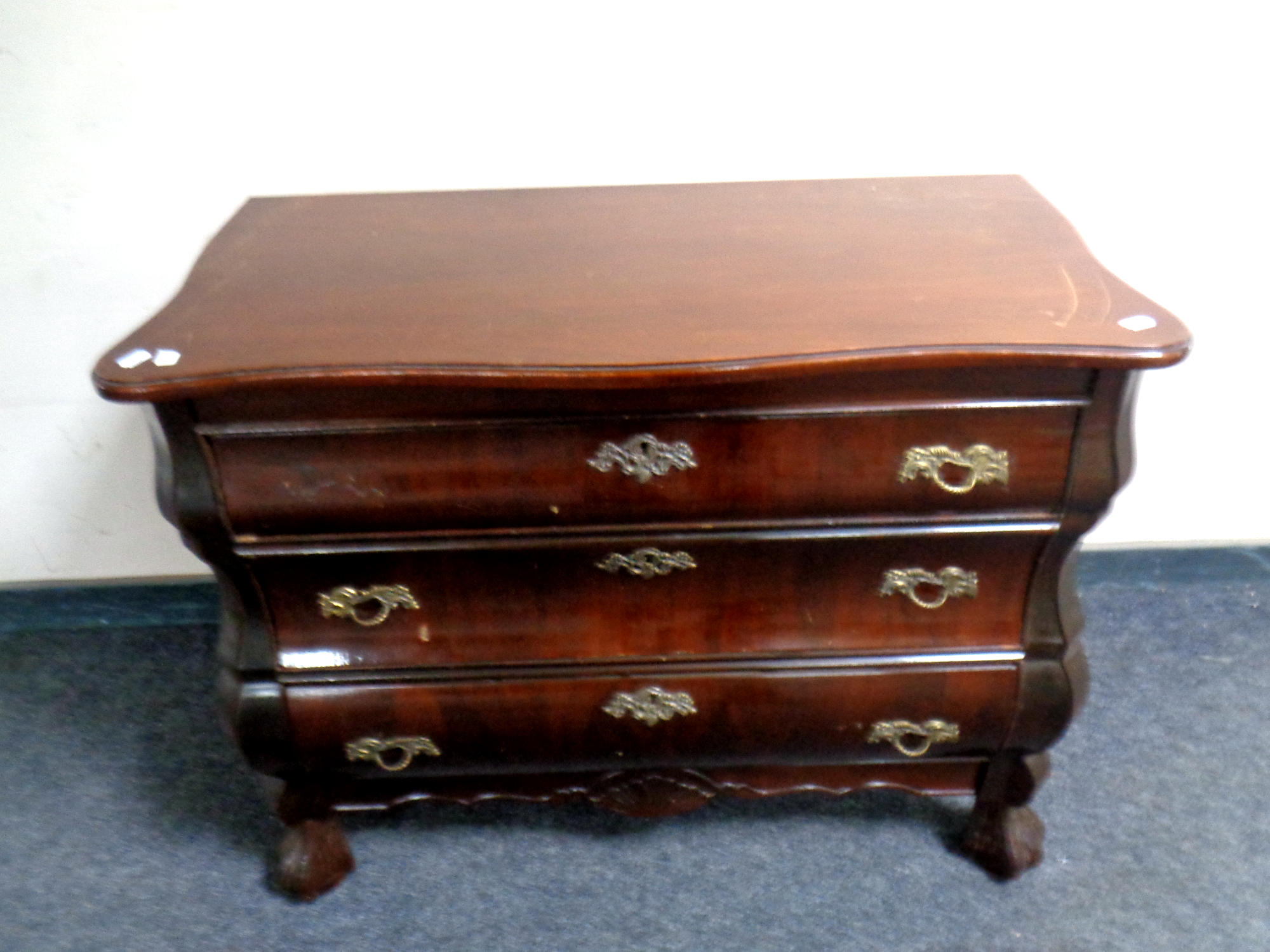 A serpentine fronted three drawer bombe chest on claw and ball feet