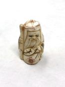 A Japanese craved bone netsuke : A village elder with a sack at his feet.