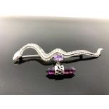 A silver snake brooch with amethyst droplet