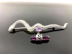 A silver snake brooch with amethyst droplet