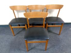 A set of four mid century teak chairs with black vinyl seats
