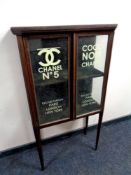 A 19th century mahogany double door display cabinet bearing later Chanel advertising