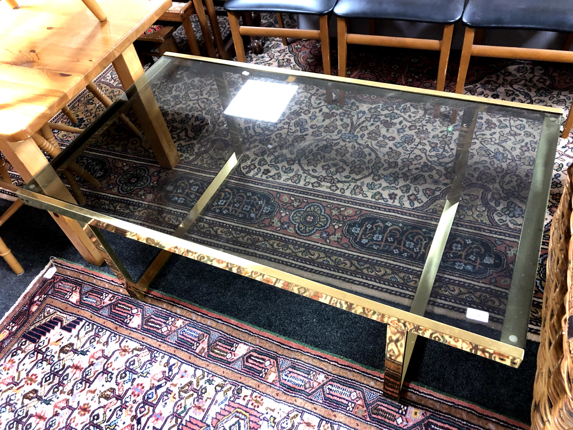 A brass framed coffee table with smoked glass top